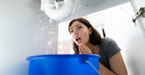 woman behind bucket watching leaking water from pipes