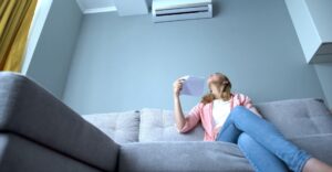 woman fanning herself while staring at air conditioning