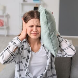 woman holding hands and pillow to ears